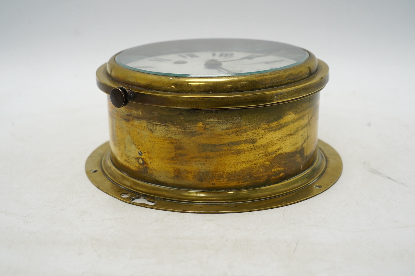 An early 20th century brass bulkhead timepiece retailed by Harrods, dial 13.5cm. Condition - poor to fair, seconds hand missing and some cracks to enamel dial